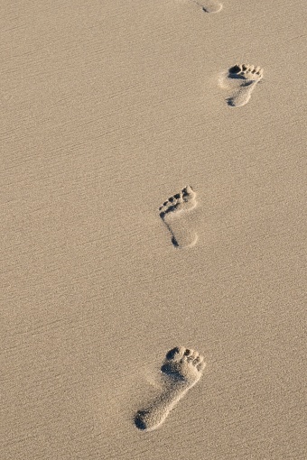 beach, wave and footprints at sunset time