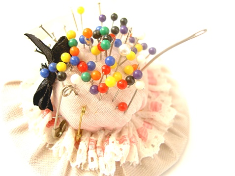 Pin cushion detail with coloured pin heads sticking out.