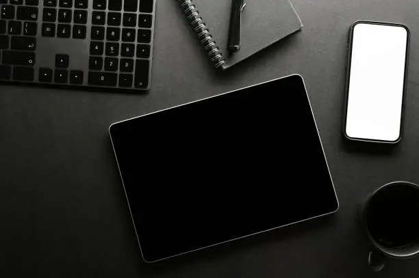 Photo of Minimal black office workspace background with smartphone mockup and tablet black screen