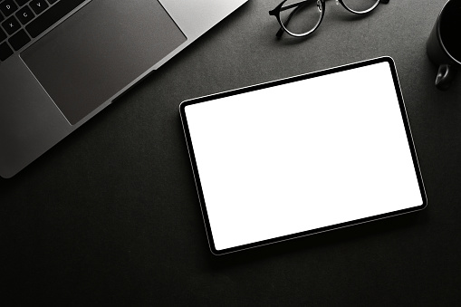 Above view, Modern minimal black workspace with laptop computer, eyeglasses and digital tablet white screen mockup.
