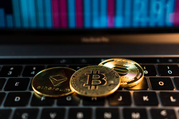 Closeup of golden Bitcoin, Ethereum and Solana coins on top of computer keyboard with financial stock market graph in the background. Cryptocurrency coin. Financial market stock photo
