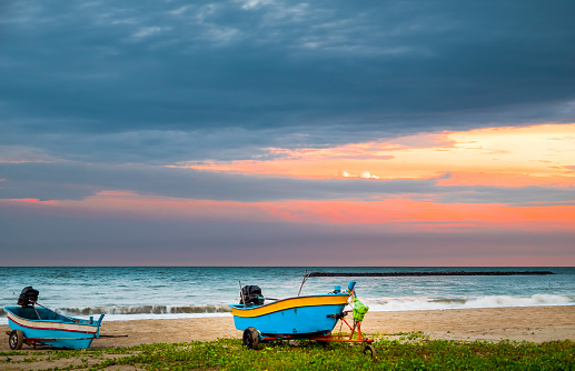 Beautiful view of the turquoise waves with the blue sky and white clouds and fisherman's boat on sandy on vacation in Hua Hin beach, Prachuap Khiri Khan Province, Thailand. Tropical colorful sand from the landscape sea. Summer vacation concept.