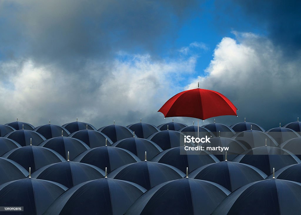 above the rest rows of umbrellas with one red one above the rest Umbrella Stock Photo