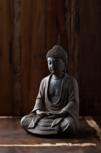 istock Meditating Buddha Statue on dark wooden background. Close up. Copy space. 1393929259