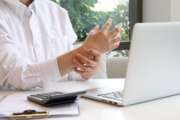 istock Woman with wrist arthritis on laptop 1393929286