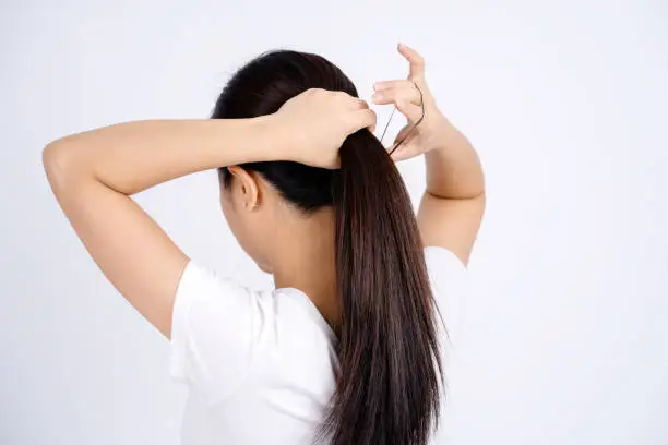 Asian woman tying her hair up isolated on a white background.