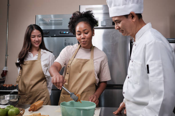 istock Senior male chef teaches cooking students to knead pastry dough for fruit pies. 1393934310