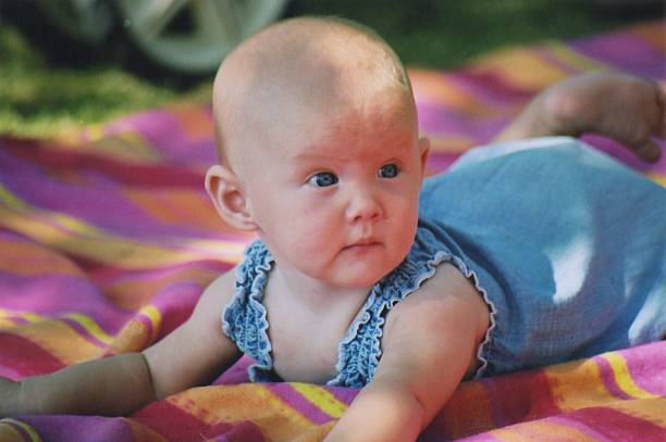 A baby girl laying on a blanket outdoors