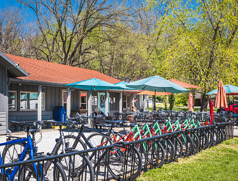 View of Midwestern restaurant and bike shop on nice sunny day; row of bicycles in foreground; outside seating behind them