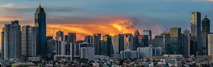 The skyline of Fort Bonifacio Global City in Metro Manila, Philippines with a thunderstorm lit up by the sunrise light.