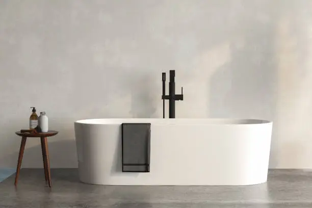 A white bathtub standing on a concrete platform with with wall background. Minimalist bathroom with concrete floor, a table with accessories on it, 3d rendering