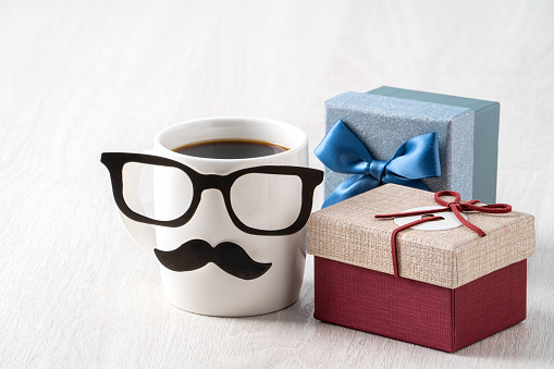 Father's day design concept. Close up of cup of coffee and gift box for daddy funny idea.