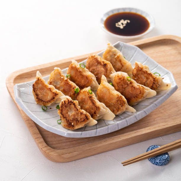 istock Pan-fried gyoza dumpling jiaozi in a plate with soy sauce on white table background. 1393945495