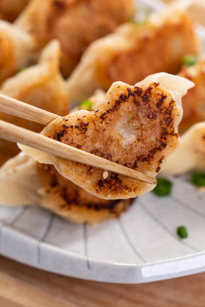 istock Pan-fried gyoza dumpling jiaozi in a plate with soy sauce on white table background. 1393945500