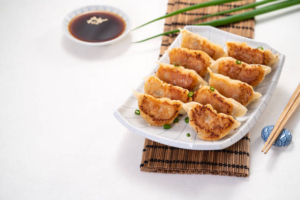 istock Pan-fried gyoza dumpling jiaozi in a plate with soy sauce on white table background. 1393945522