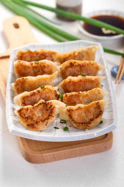 istock Pan-fried gyoza dumpling jiaozi in a plate with soy sauce on white table background. 1393945631