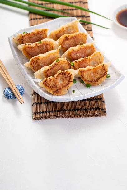 istock Pan-fried gyoza dumpling jiaozi in a plate with soy sauce on white table background. 1393945668