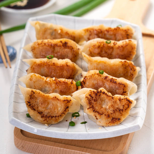 istock Pan-fried gyoza dumpling jiaozi in a plate with soy sauce on white table background. 1393945691