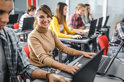 Happy woman having a computer class with her classmates and looking at camera.