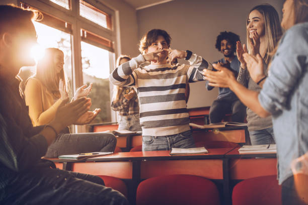 istock Young students applauding their friend in the classroom. 1393948308
