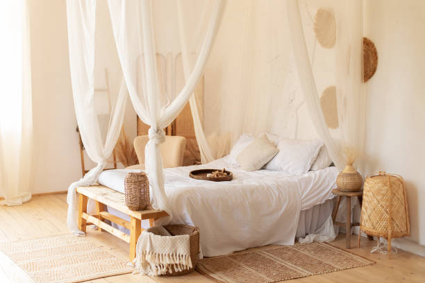 istock interior white bedroom in boho  style with coffe table,straw lamp and comfortable bed with pillows, copy space. bed with flowing white curtains. Cozy scandinavian decoration room. hygge decor at home 1393948494