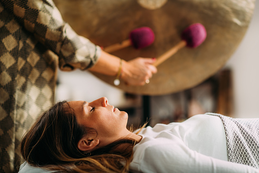 Playing gong in sound bath therapy