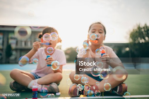 istock Little girl blowing soap bubbles 1393951739