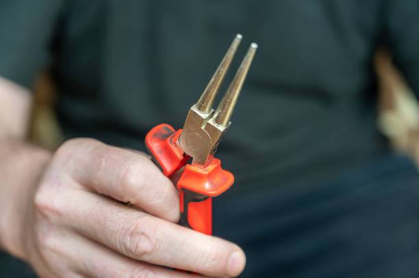 istock The hand of a mature man holding round pliers. Hand-held locksmith tool with smooth surface finish and diameter tapering toward the tips. 1393955705