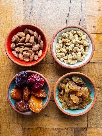 Turkish traditional food concept: Variety of organic and delicious dry fruits and nuts on wooden table. Natural daylight falling from window. Healthy eating for hormonal and weight balance. Food background with copy space.