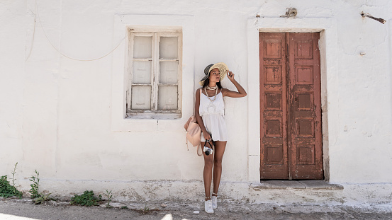 Smiling Asian woman leaning back on a wall in old town Volimes in Zakynthos Greece