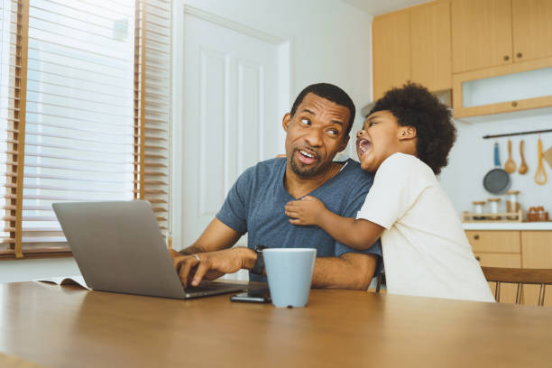 istock African American father working from home on laptop while his Cheerful son distracts 1393956747