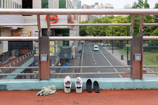 Shanghai, China - April 27, 2022: It has been the 27th day since Puxi area lockdown in Shanghai and some food delivery-guy is drying his shoes on the pedestrian overpass.