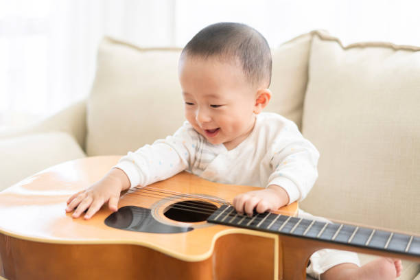 little toddler girl playing ukulele in music class.