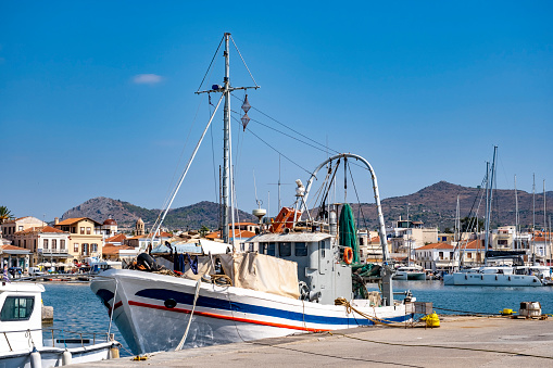 Greek culture and Travel destination: A day trip to Aegina Island, Greece, Aegean sea. Background with copy space. View from the port with sailing and fishing boats in front of town.