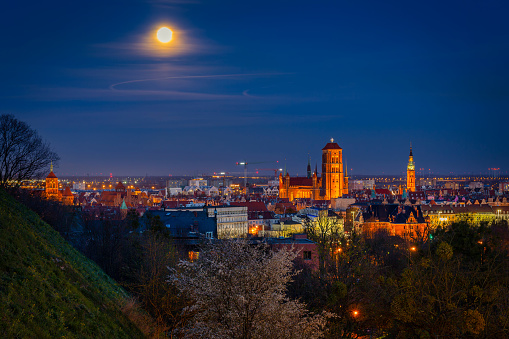 A full moon rising over the city of Gdansk at dusk. Poland