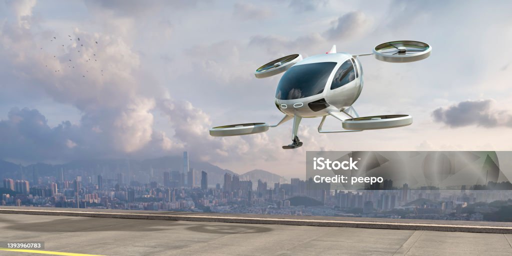 eVTOL Electric Vertical Take Off and Landing Aircraft About To Land Near City A generic white electric powered Vertical Take Off and Landing eVTOL aircraft with four rotors, coming in to land on roof top helipad with high city city buildings in the background. The sky is bright with clouds and it's late afternoon / early morning. Futuristic Stock Photo