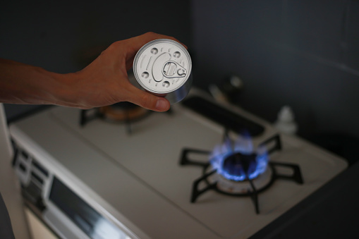 A man trying to heat a can on a gas stove