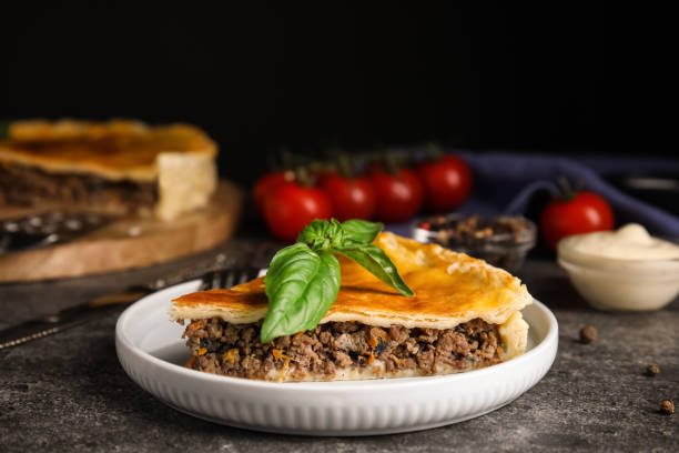 pedazo de delicioso pastel con carne picada y albahaca servido sobre mesa gris, primer plano - pastel de carne fotografías e imágenes de stock