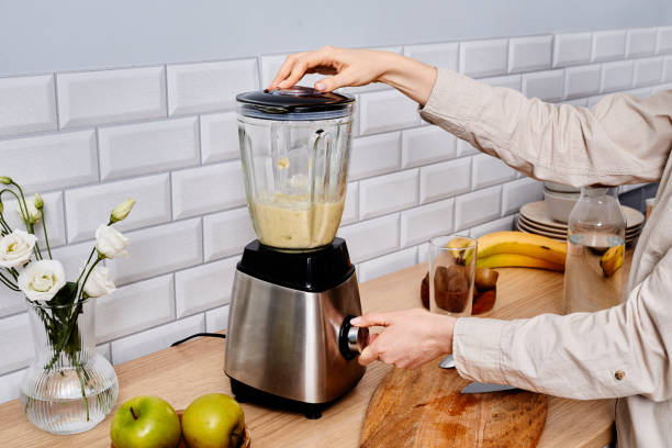 woman making fresh juice in blender - blender apple banana color image imagens e fotografias de stock