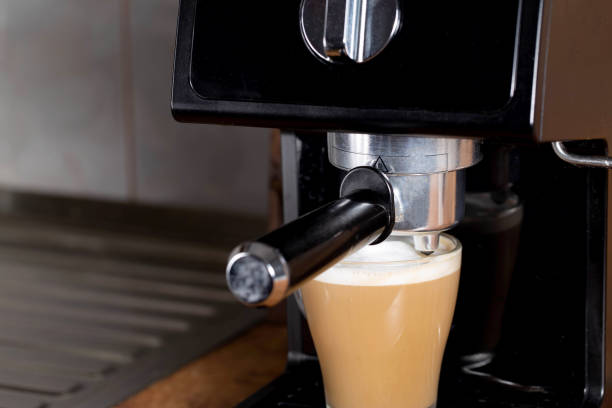 istock Making coffee with cappuccino milk in a cappuccino machine with a manual cappuccino maker on the background of a wooden table top. Close-up 1393967090