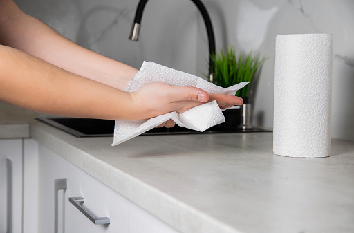 A man wipes his hands with a paper towel in the kitchen. Napkins for care, domestic