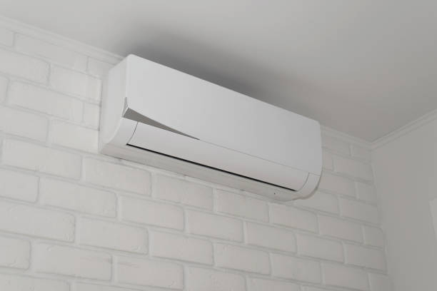istock Fashionable modern white air conditioner mounted on brick wall inside house. Side view 1393970281