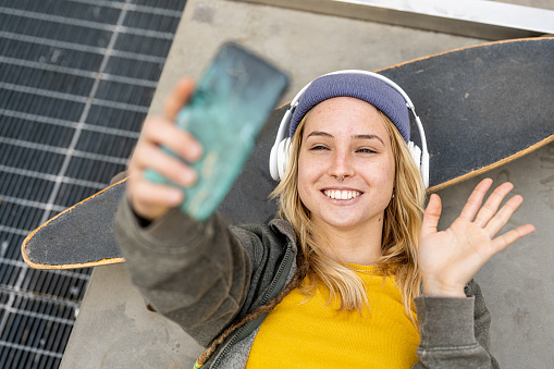 portrait of a young smiling woman using smartphone to make video call, generation z lifestyle