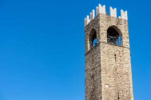 Brescia downtown. Closeup of the medieval Tower of the Broletto Palace called Torre del Pegol or Torre del Mercato or Torre del Popolo. XII-XIII century. In Cathedral square (Piazza del Duomo or Piazza Paolo VI). Lombardy, Italy, Europe.
