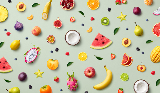 Colorful pattern of various fresh whole and sliced ripe fruits and berries, top view, flat lay. Exotic summer food concept.