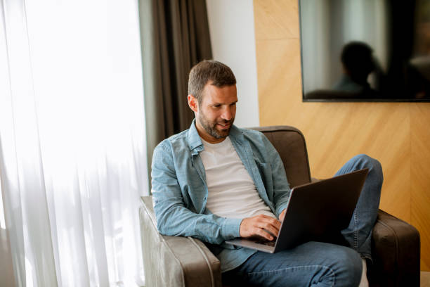 istock Young man using laptop in the living room 1393977935