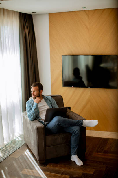istock Young man using laptop in the living room 1393977938