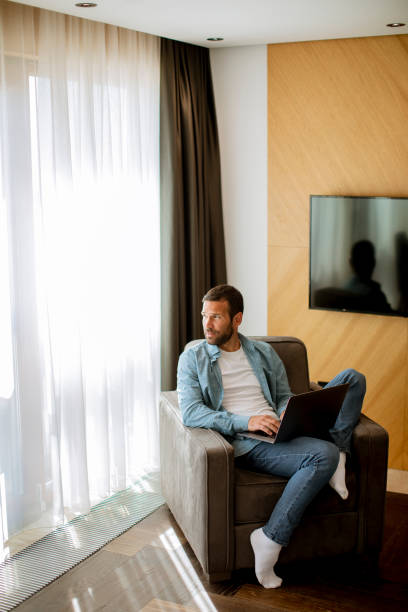 istock Young man using laptop in the living room 1393977961