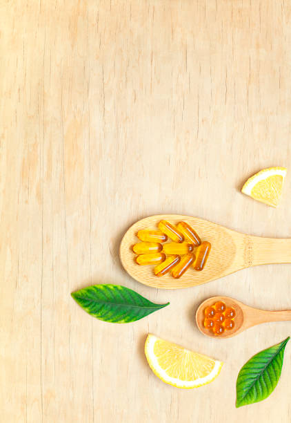 ビタミン入りスプーンは木製のテーブルの上に横たわっています - vitamin a nutritional supplement pill capsule ストックフォトと画像