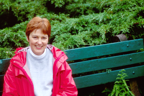 Lady in Red contrasted with green foliage and bench